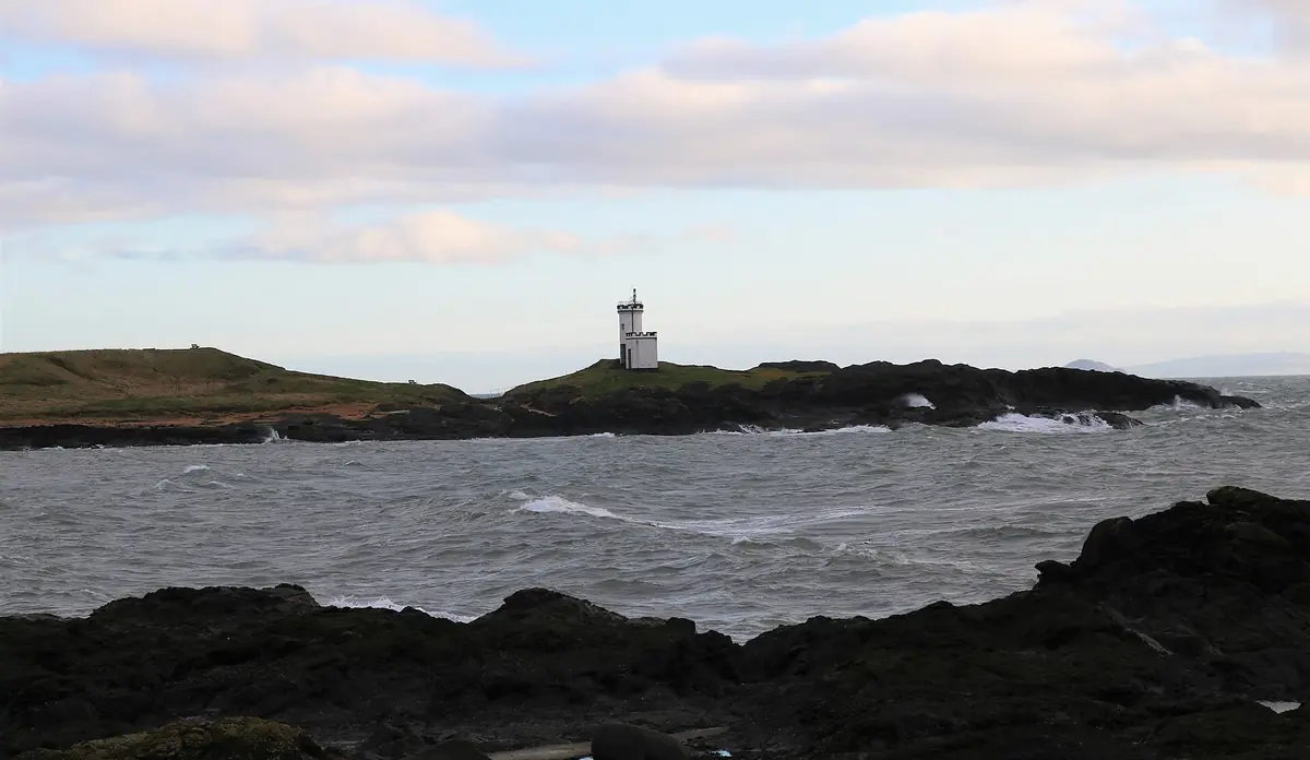 Il faro bianco di Elie Ness sugli scogli, con il mare mosso e il cielo invernale